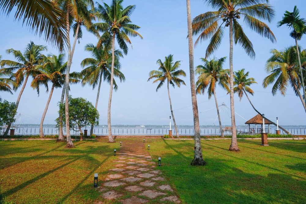A palm-lined garden path leading to the Vembanad backwaters